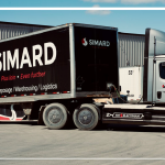 Brandon Abraham et Sylvie Lemay discutent des camions électriques chez Simard Transport, et sur cette photo, l'un des camions électriques et une nouvelle remorque noire.