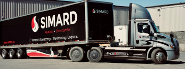 Brandon Abraham et Sylvie Lemay discutent des camions électriques chez Simard Transport, et sur cette photo, l'un des camions électriques et une nouvelle remorque noire.